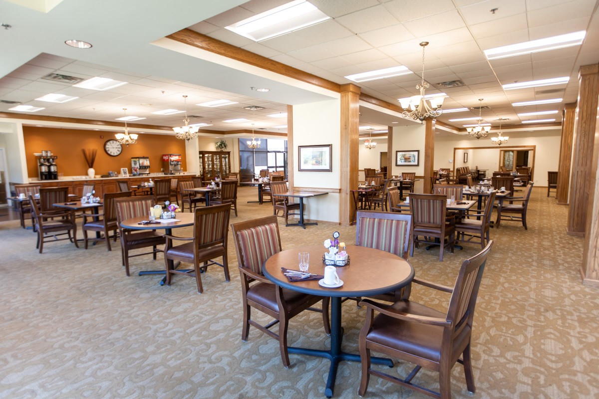 A spacious dining area featuring wooden tables and chairs, with warm lighting and an inviting atmosphere.