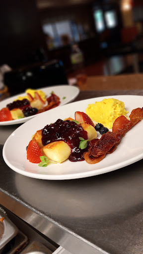 A delicious breakfast featuring a colorful fruit medley, scrambled eggs, and crispy bacon.