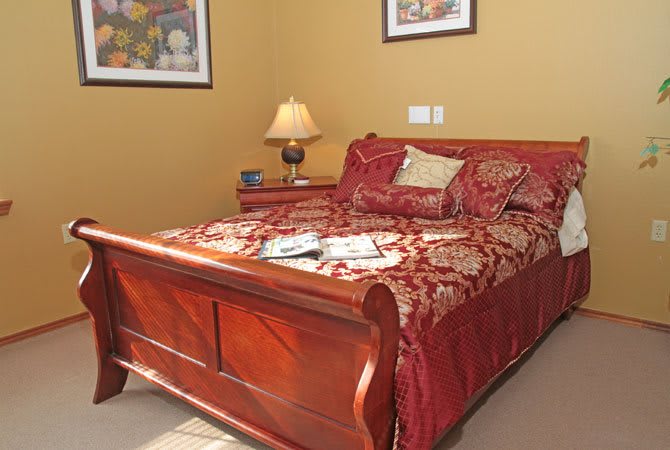 A cozy bedroom with a wooden bed, decorative bedding, and a lamp on the nightstand.