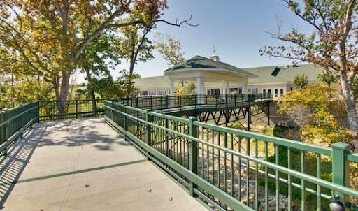A scenic view of a bridge leading to a modern building surrounded by trees.