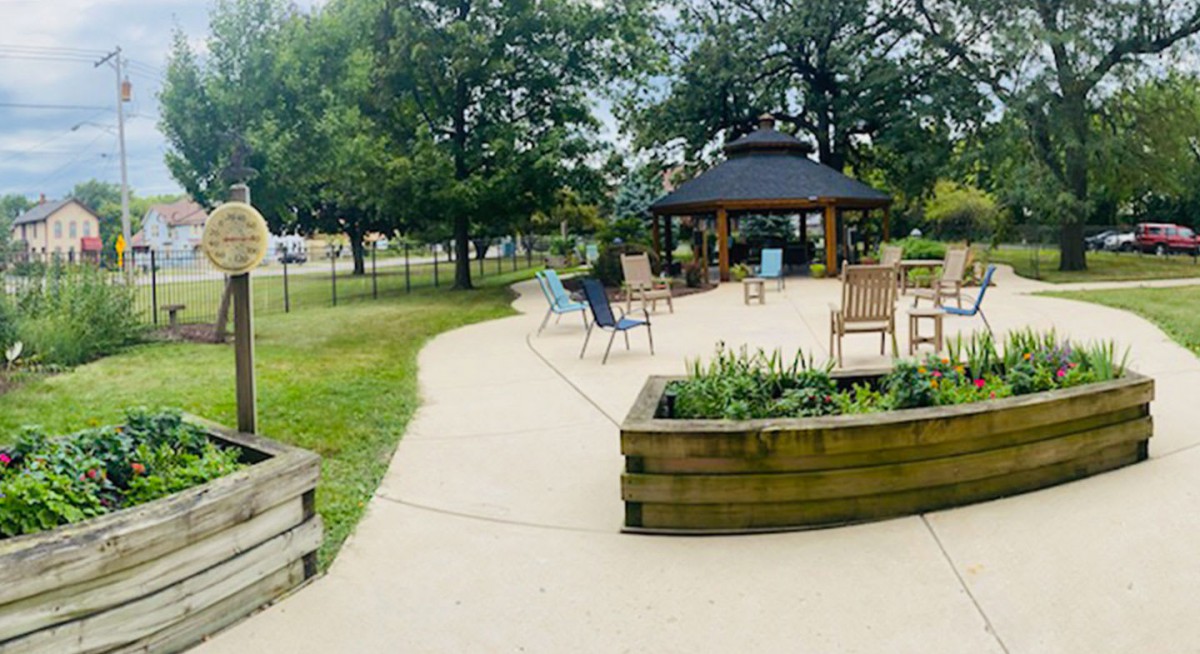 A serene park setting with a gazebo and seating area surrounded by trees.