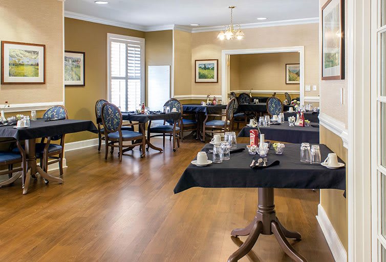 An elegant dining room with neatly arranged tables and chairs, featuring large windows and tasteful decor.