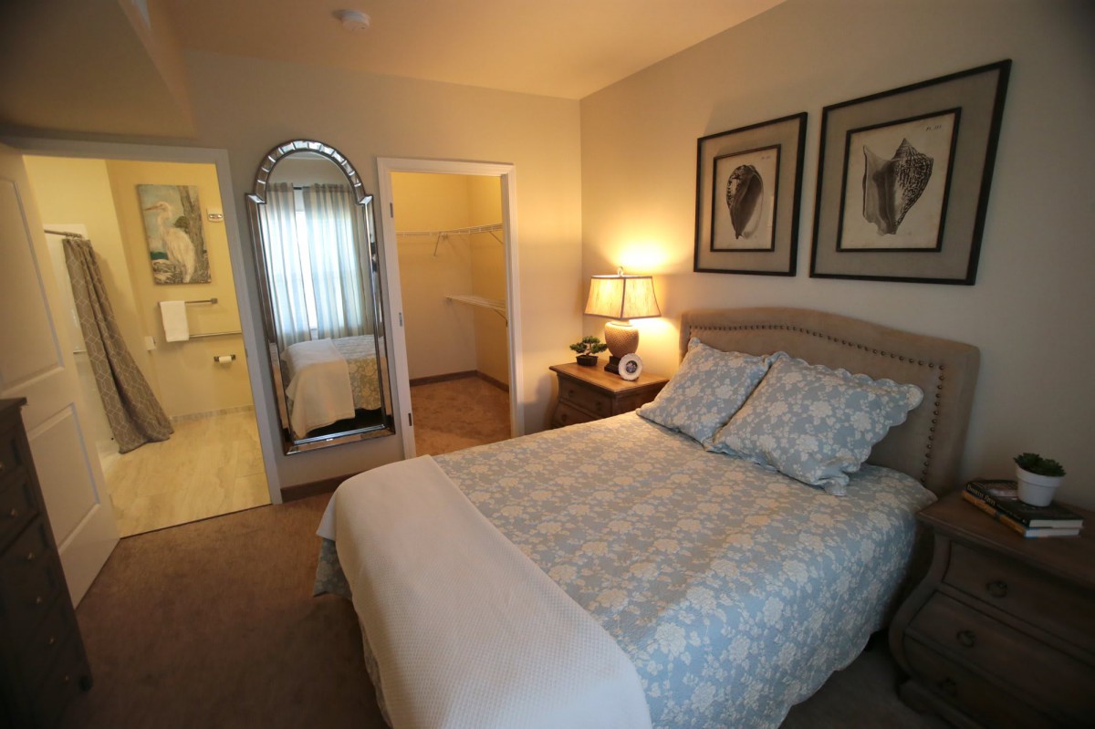 A cozy bedroom with a neatly made bed, decorative artwork, and soft lighting.
