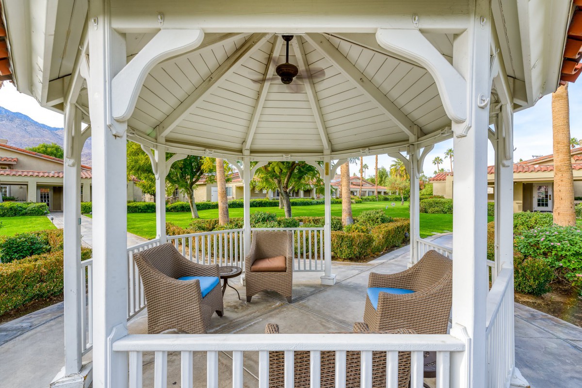 An inviting gazebo with wicker chairs set amidst a lush garden.