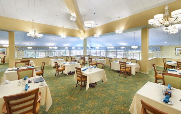Spacious dining area with neatly arranged tables and chairs, featuring ample lighting and large windows.