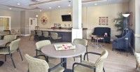 A modern waiting area with tables and chairs, featuring a TV mounted on the wall.