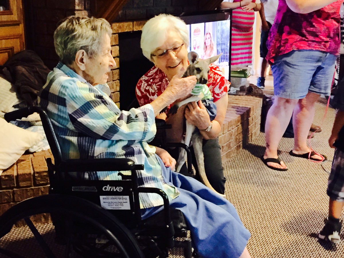 Elderly individuals enjoying a moment with an animal at a nursing home.