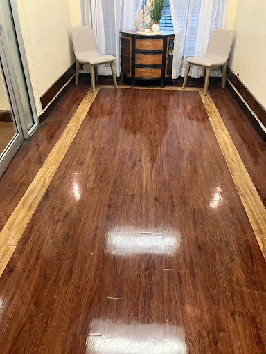 A well-polished wooden floor with a decorative border, complemented by two chairs in the background.