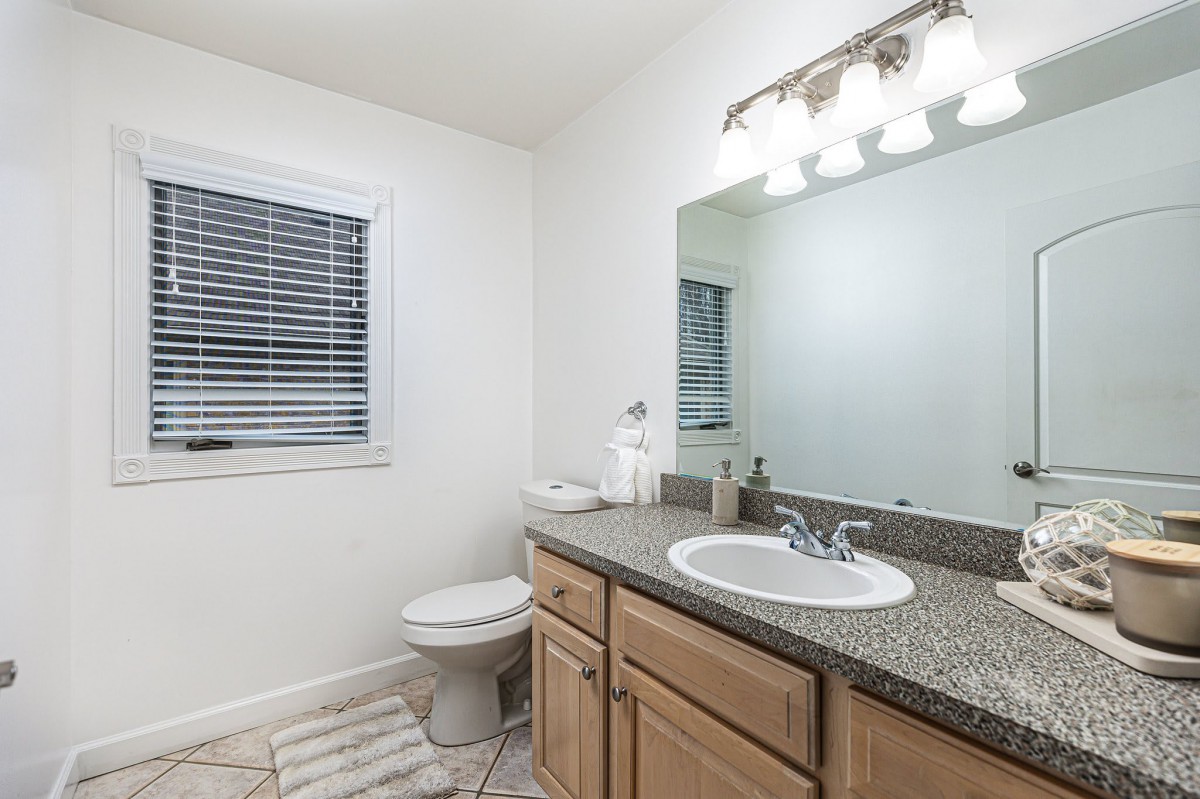 A clean and bright bathroom with a large mirror and granite countertop.