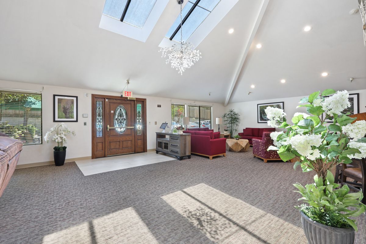 A spacious living room with skylights, elegant chandelier, and comfortable seating.