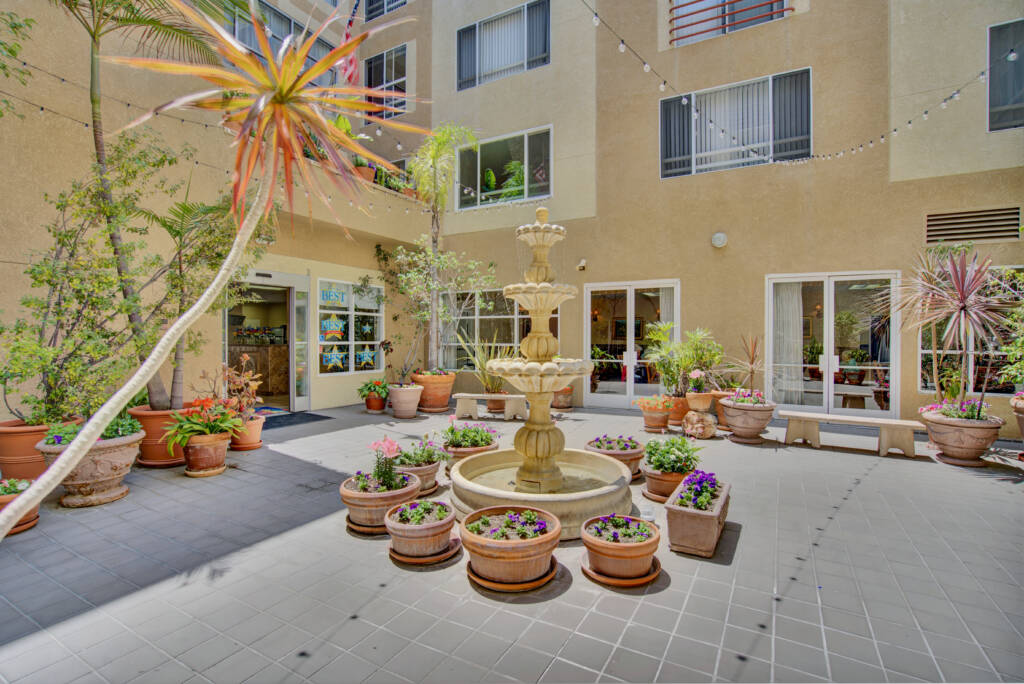 A serene courtyard with a central fountain surrounded by potted plants.