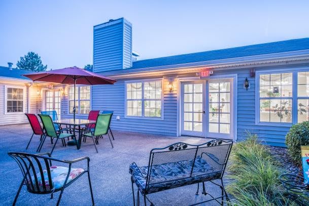 A cozy patio with colorful chairs and an umbrella, adjacent to a residential house in the evening.