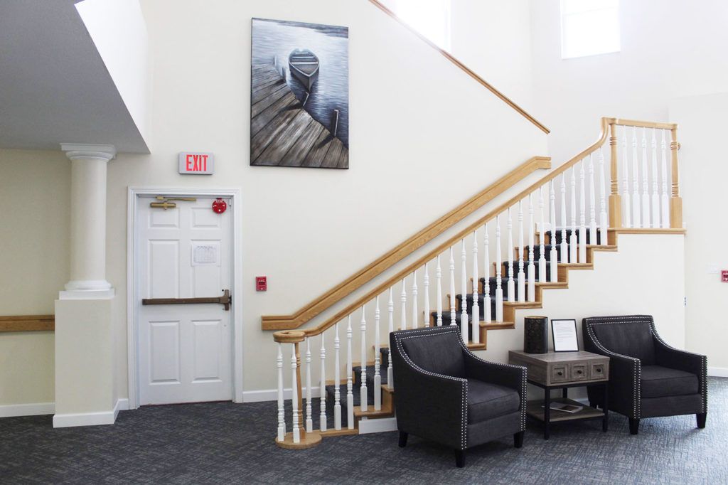 A modern lobby features a staircase, seating area, and wall artwork.