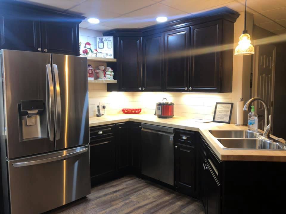 A modern kitchen with dark cabinets and stainless steel appliances.