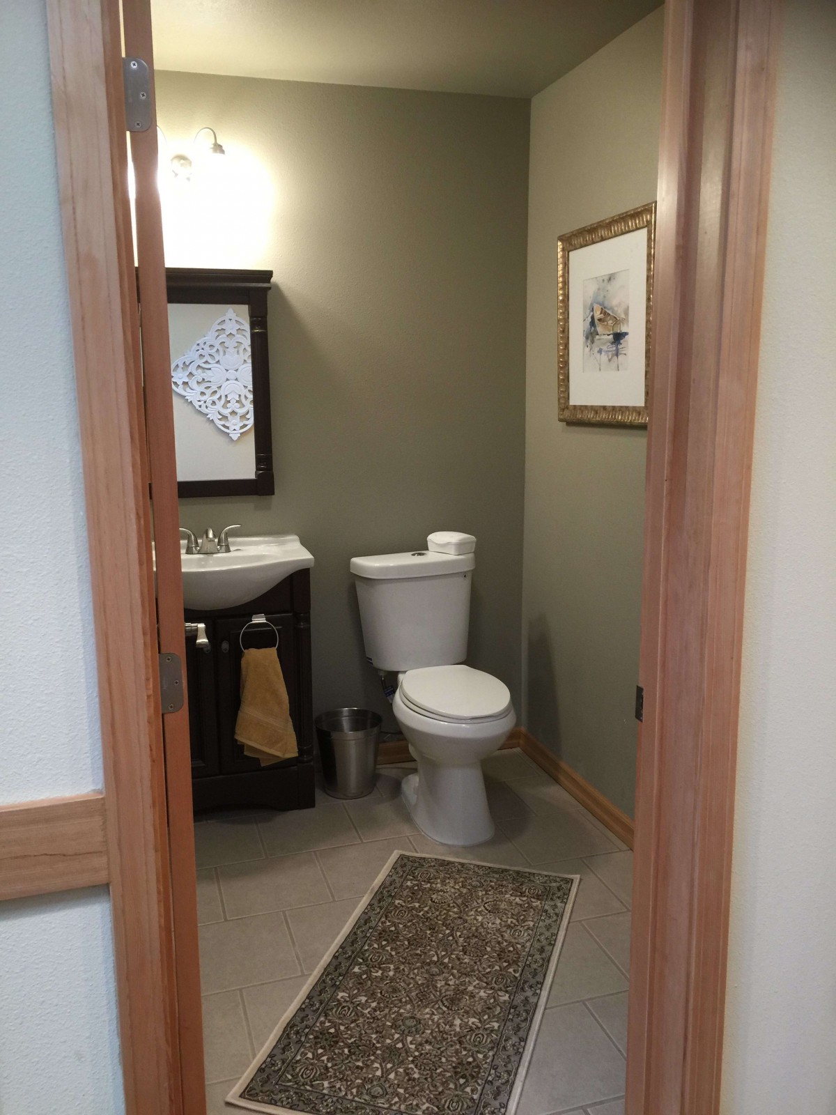 A small bathroom featuring a toilet, sink, and wall decor.