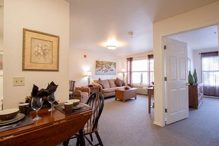 A cozy living room with a comfortable sofa, dining area, and tasteful artwork on the walls.