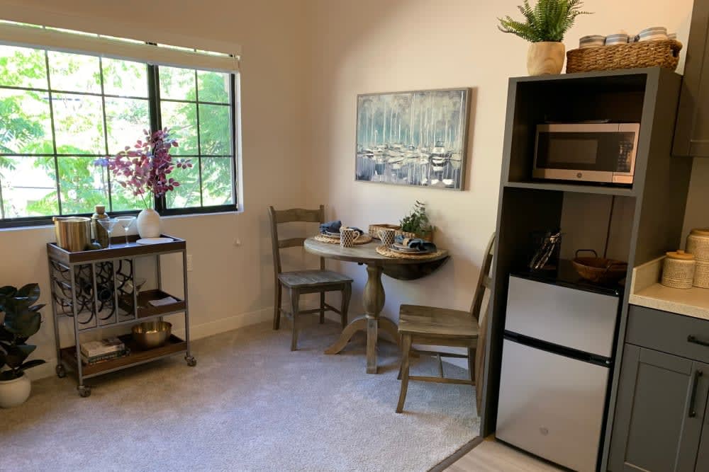 A cozy room with a small table and chairs near a window, decorated with plants and artwork.