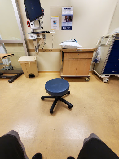 A view of a medical exam room featuring a stool and various healthcare equipment.