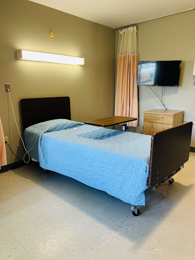 A hospital room featuring a bed with blue linens and a wall-mounted television.