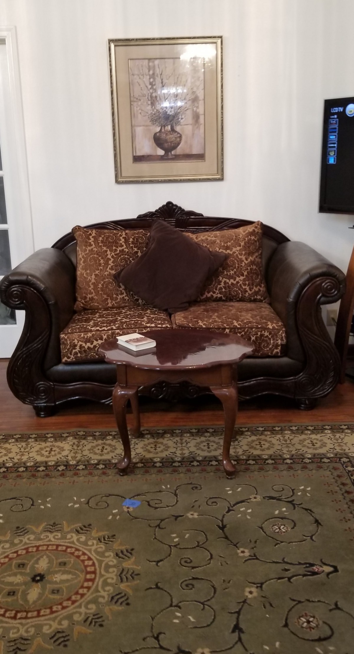A classic-style sofa with patterned cushions, accompanied by a wooden coffee table in a cozy living room setting.
