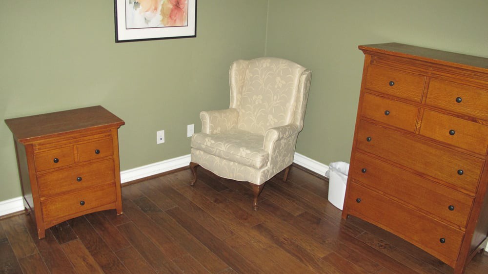 A cozy room corner with an upholstered chair and wooden furniture.