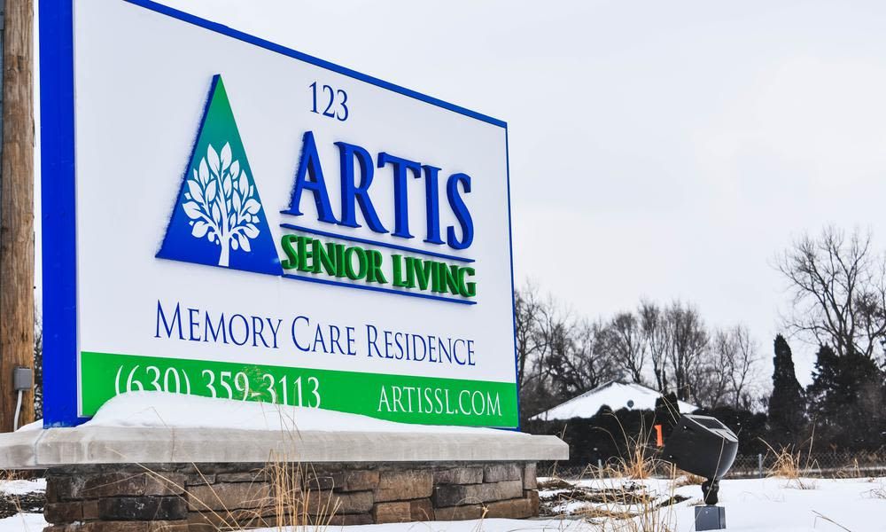 Sign for Artis Senior Living's Memory Care Residence with a snowy background.