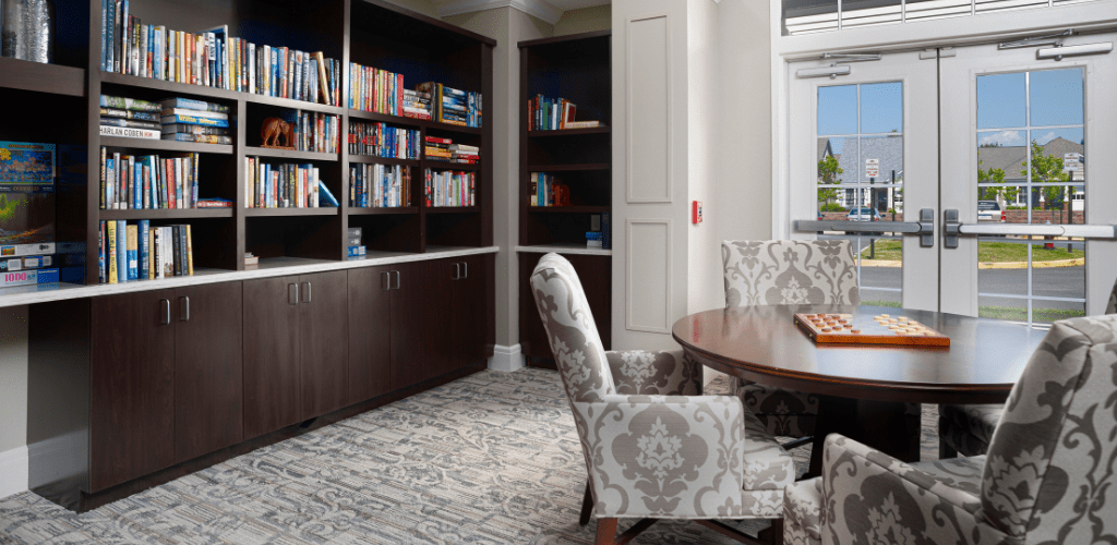 A cozy library corner with shelves full of books, a round table, and patterned chairs.