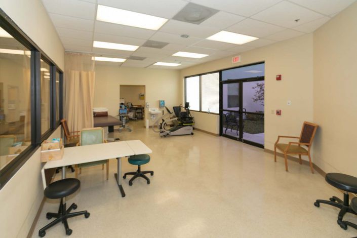 A spacious physical therapy room equipped with exercise machines and seating areas.