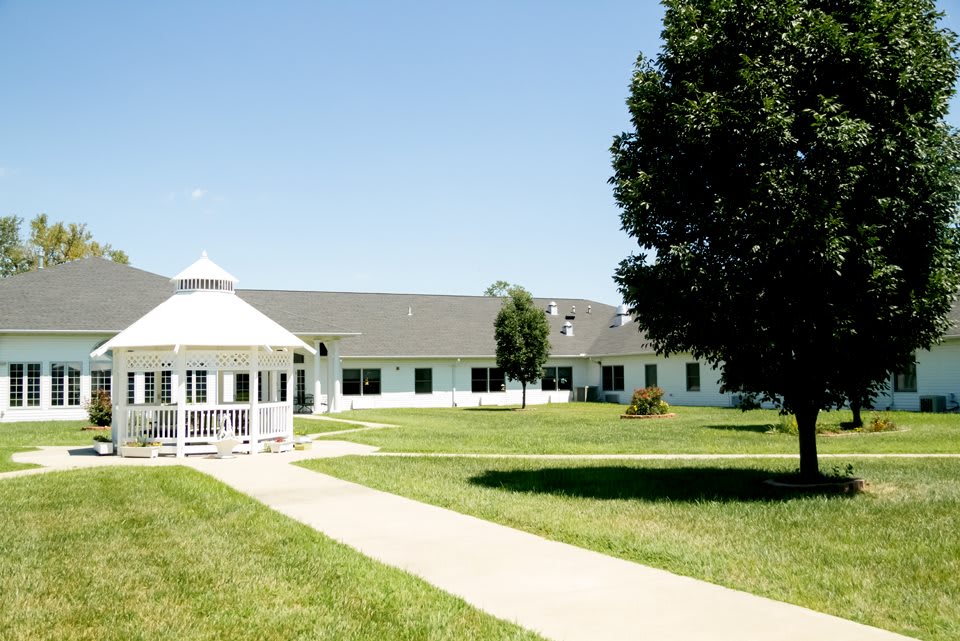 A sunny day at a facility with a gazebo, pathway, and surrounding greenery.
