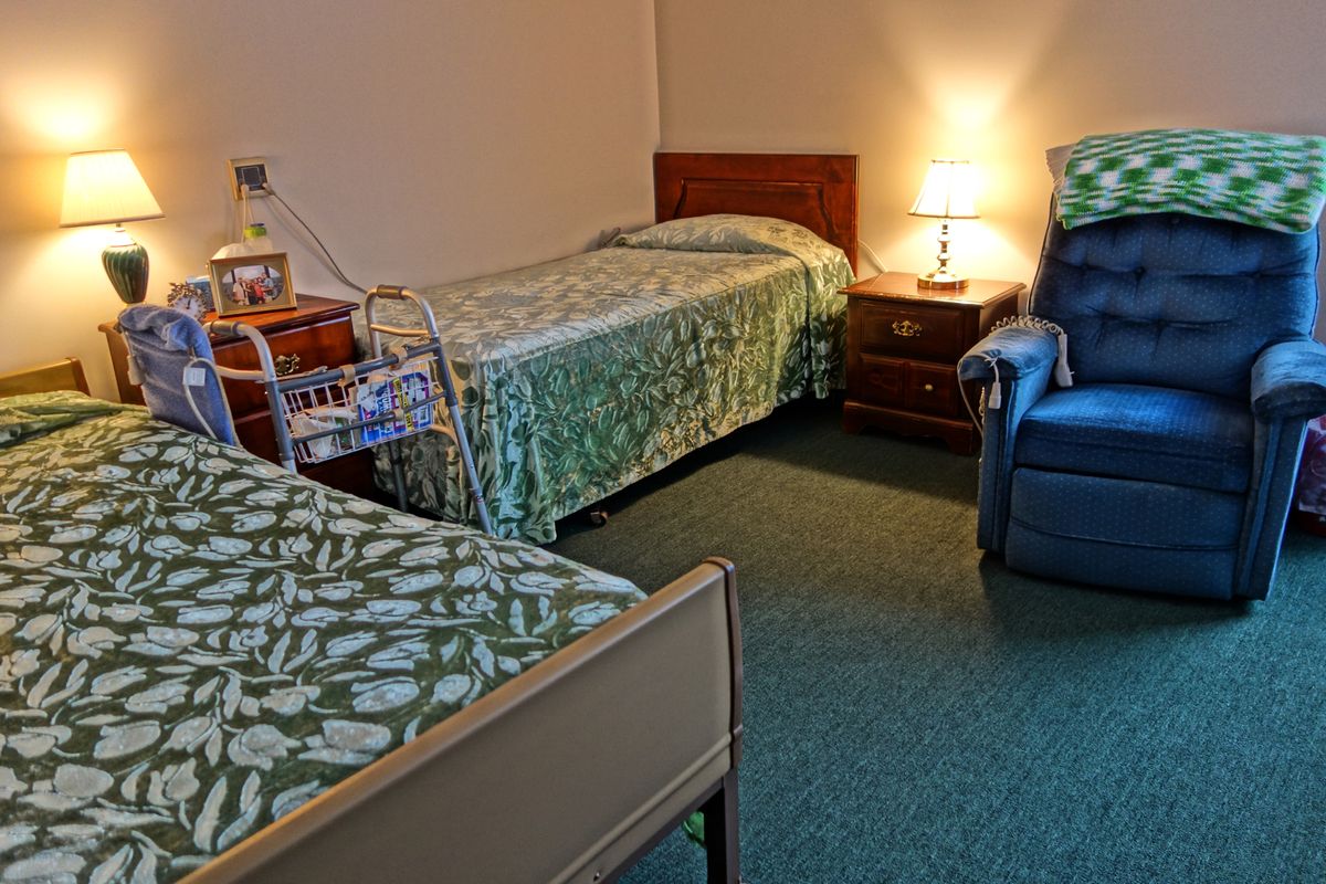 A cozy room with two single beds, a lamp, and a comfortable chair.