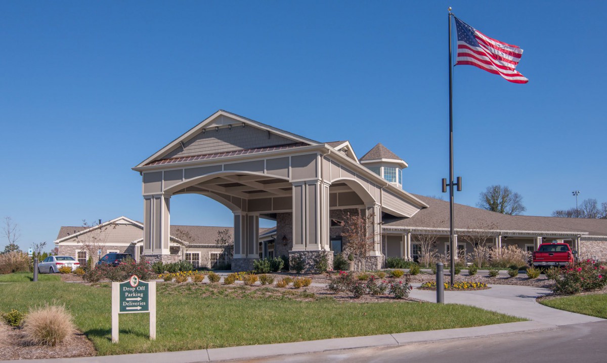 A well-maintained building entrance with an American flag and landscaped surroundings.