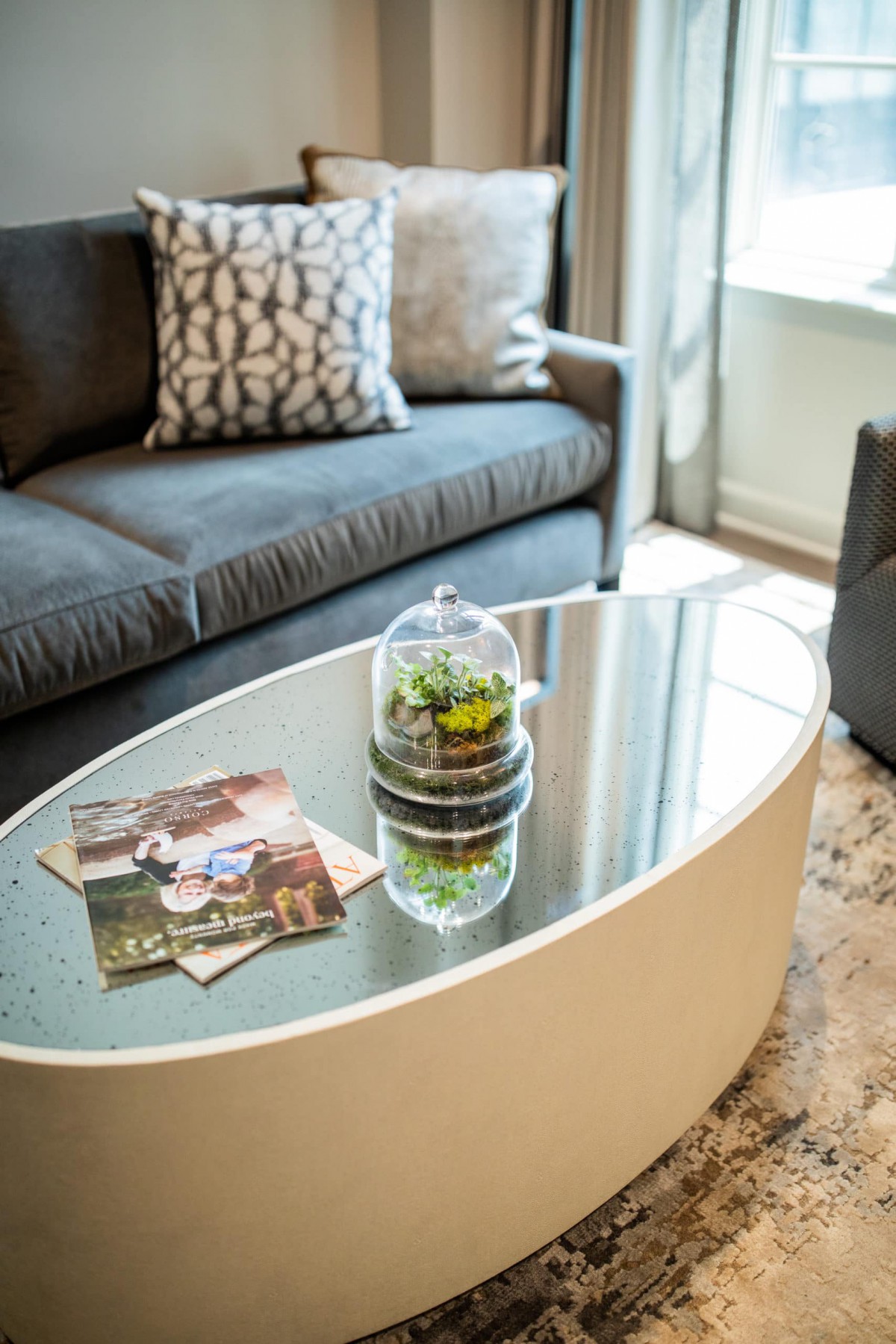 A cozy living room with a modern coffee table adorned with magazines and a small plant centerpiece.