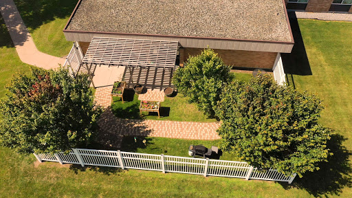 A serene garden view featuring a pathway, seating area, and lush greenery.