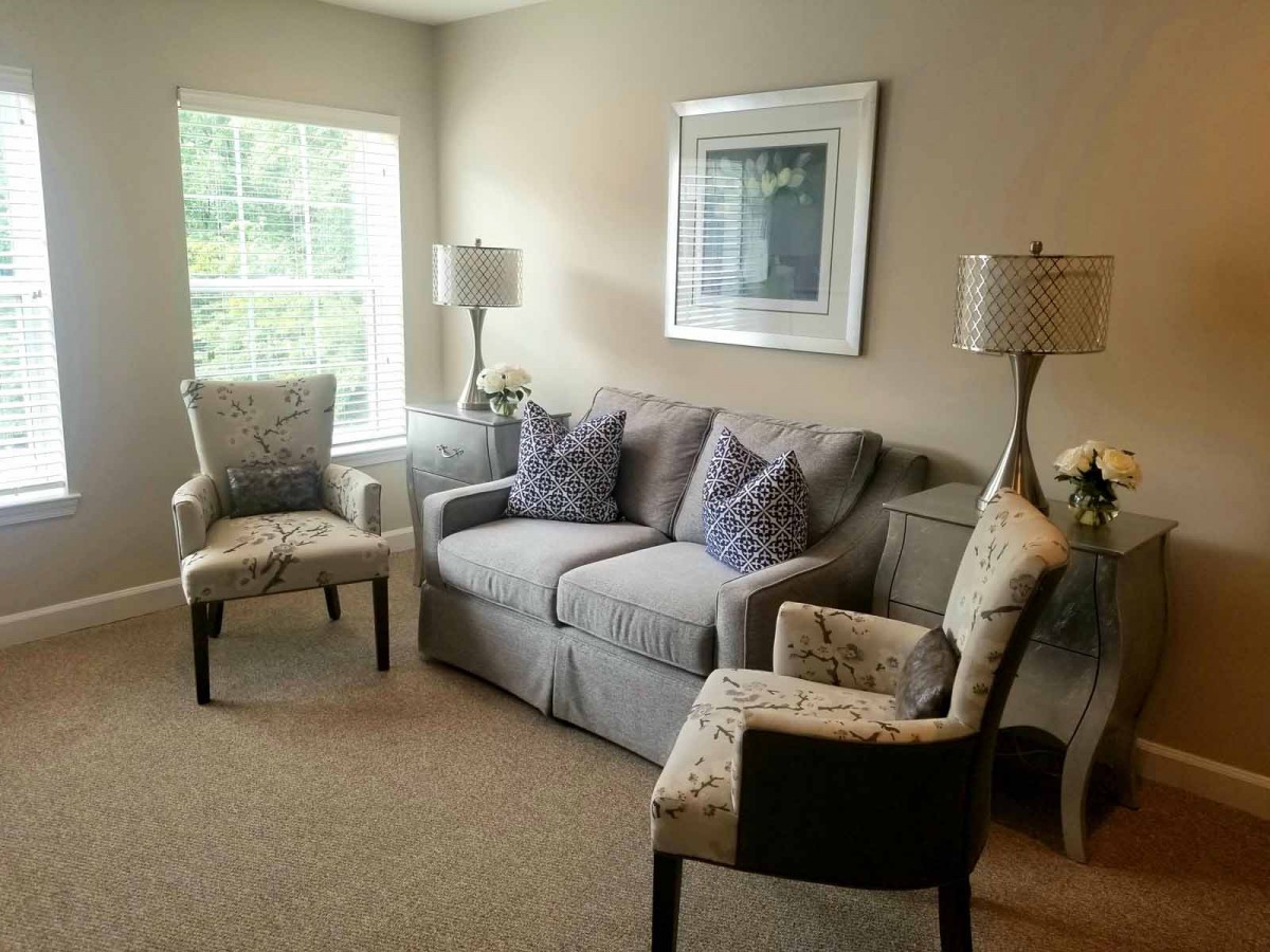 A cozy living room featuring a grey sofa, patterned armchairs, and stylish lamps.