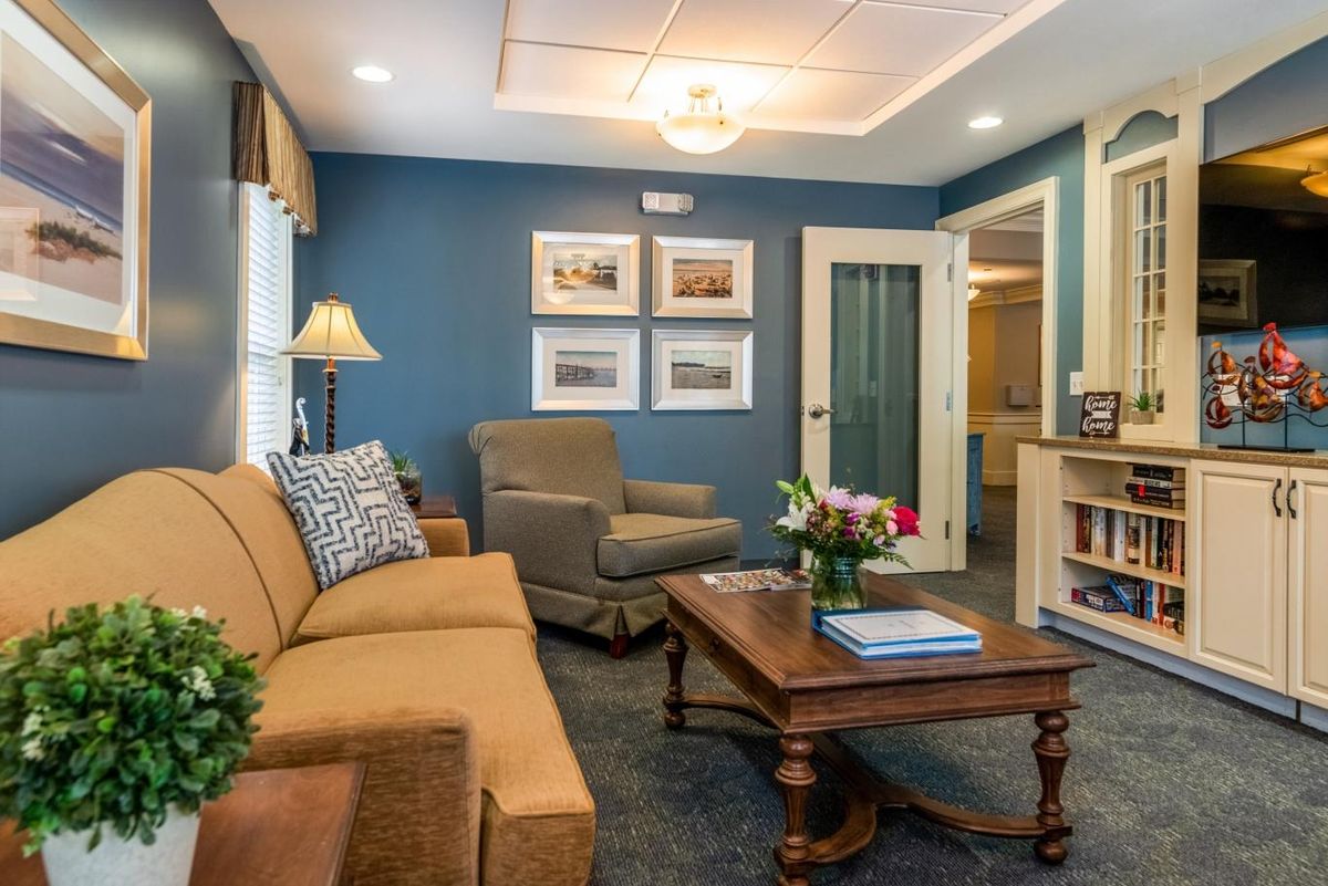 A cozy living room featuring a comfortable sofa and armchair, complemented by a wooden coffee table and warm lighting against a blue accent wall.