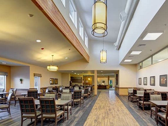 A spacious dining area with tables and chairs, featuring elegant lighting and a wooden floor.