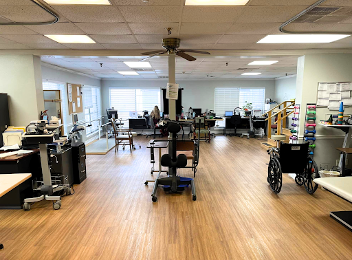A spacious therapy room equipped with various medical devices and wheelchairs, designed for rehabilitation services.