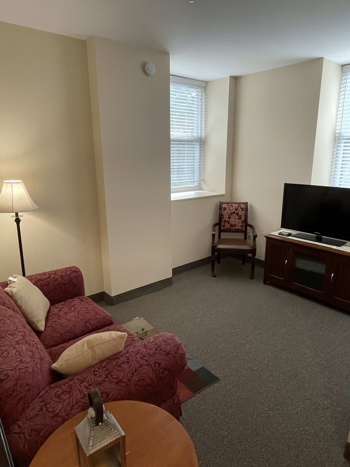 A cozy living room with a sofa, armchair, and television.