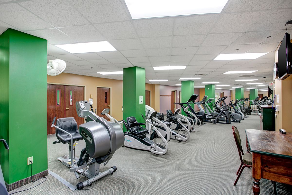 A spacious gym with exercise equipment including treadmills and ellipticals lined up for use.