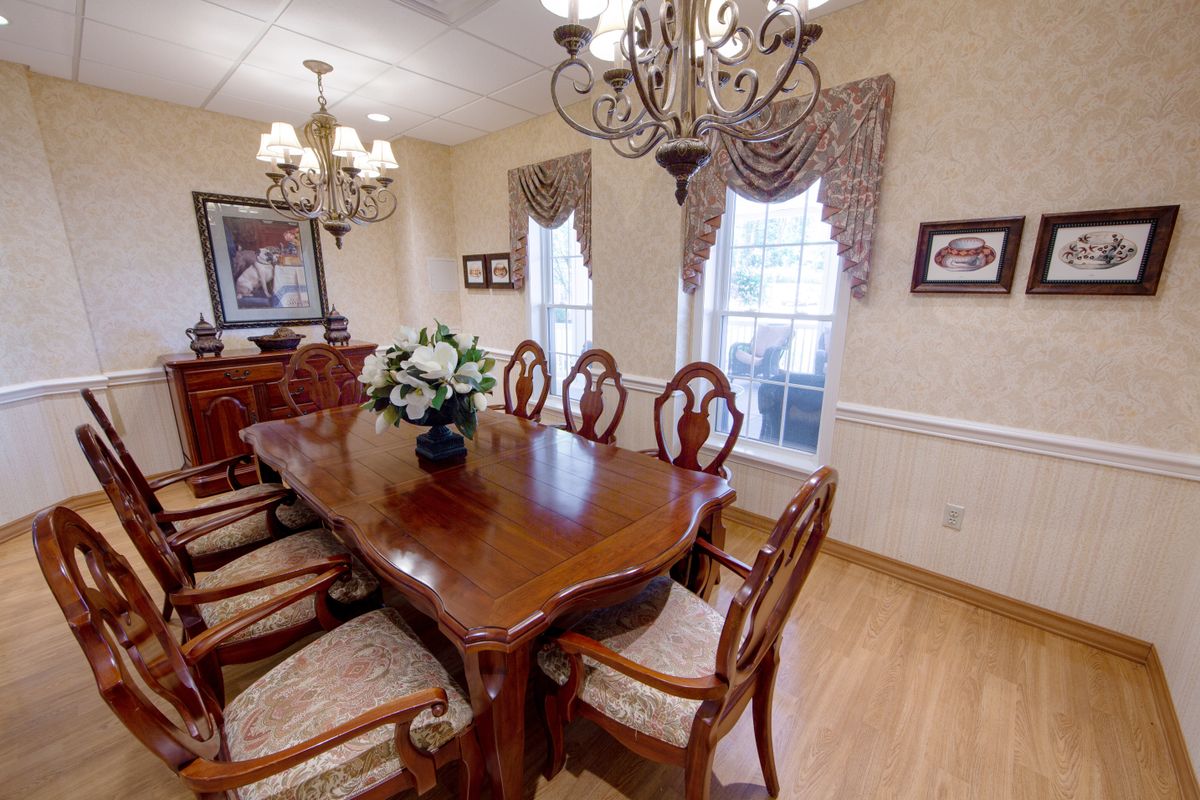 A classic dining room with a wooden table, elegant chairs, and chandeliers.