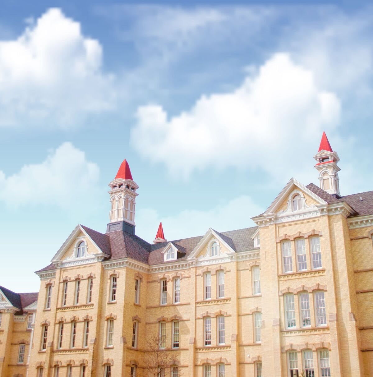 A historic building with red-roofed towers under a blue sky with clouds.