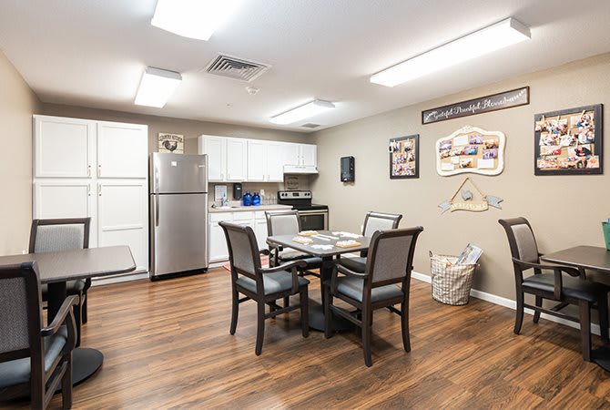 A modern apartment kitchen and dining area with a table, chairs, and stainless steel appliances.