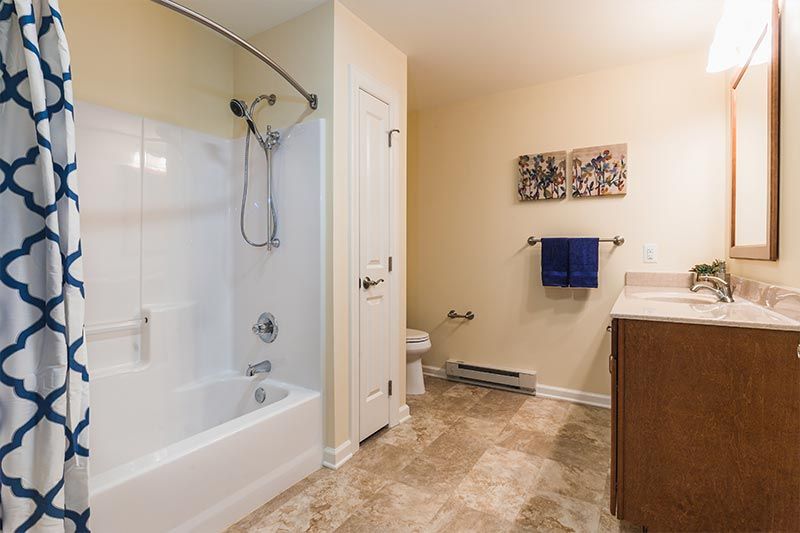 A modern bathroom featuring a bathtub with a shower, a sink, and a toilet on tiled flooring.