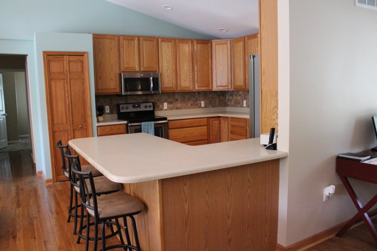 A modern kitchen with wooden cabinets, a spacious countertop, and bar stools.