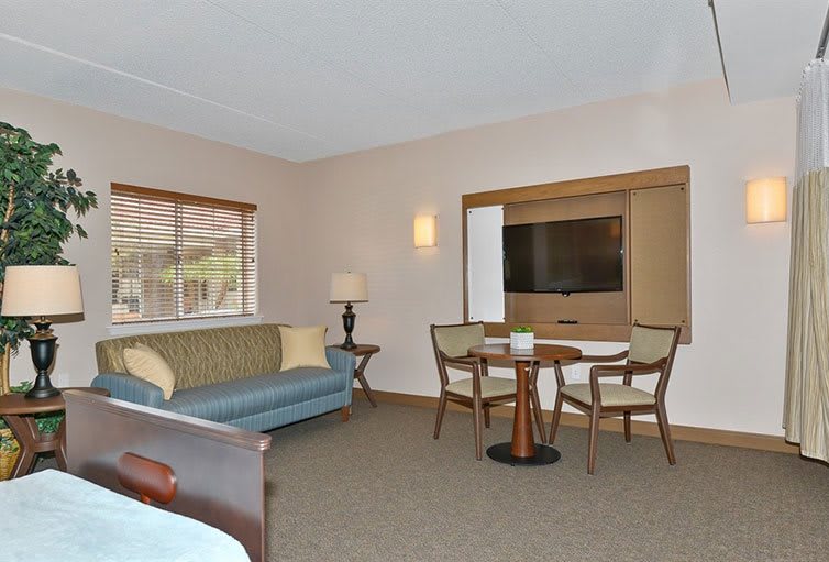 A spacious hotel room with a seating area, TV, and large window.
