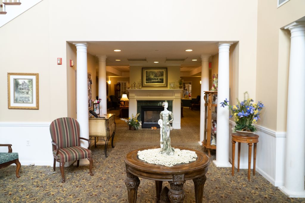 A beautifully decorated lobby area featuring a central table with a statue, surrounded by comfortable seating and a fireplace.