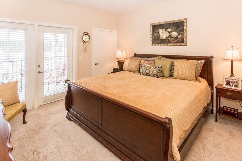 Cozy bedroom with a wooden bed, decorative pillows, and a lamp.