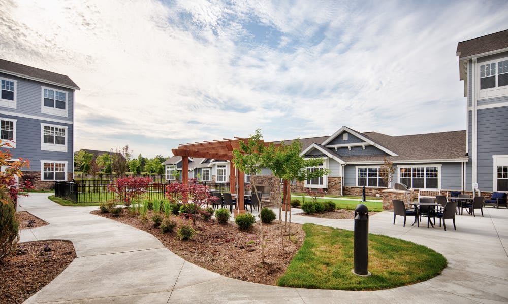 A scenic view of a landscaped garden area with pathways and residential houses under a cloudy sky.