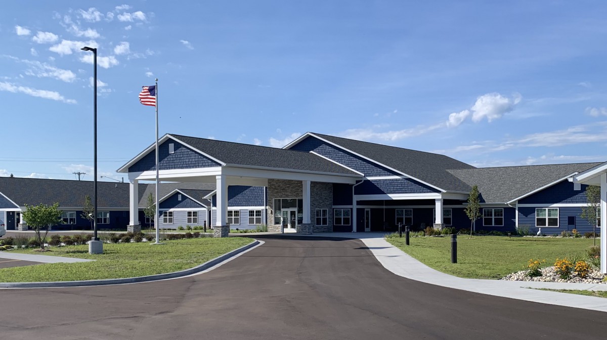 A modern building with a prominent entrance, surrounded by well-maintained landscaping and an American flag flying nearby.
