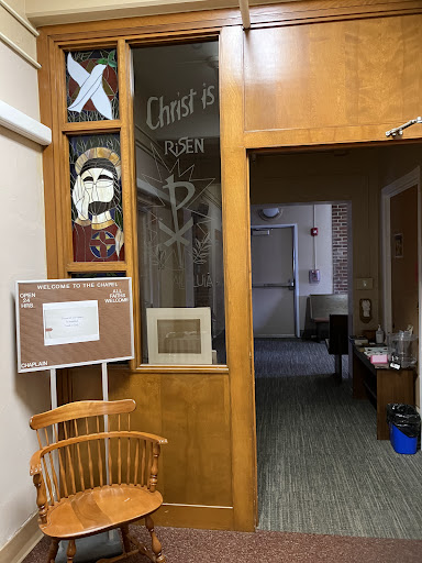 A view of an office space with wooden elements, artwork on the walls, and a doorway leading to another area.